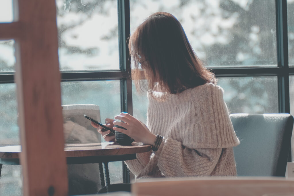 Woman drinking coffee looking at cell phone